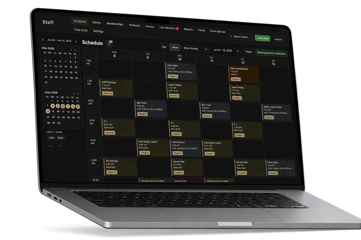 Laptop showing a dark branded staff schedule: week grid, mini calendars, trainer assignments, and check-in buttons.